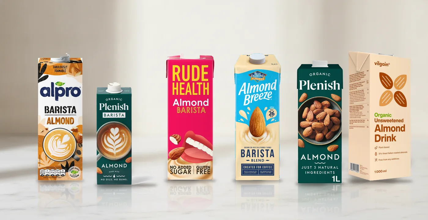 Six almond milk cartons lined up for coffee testing - UK brands reviewed July 2026