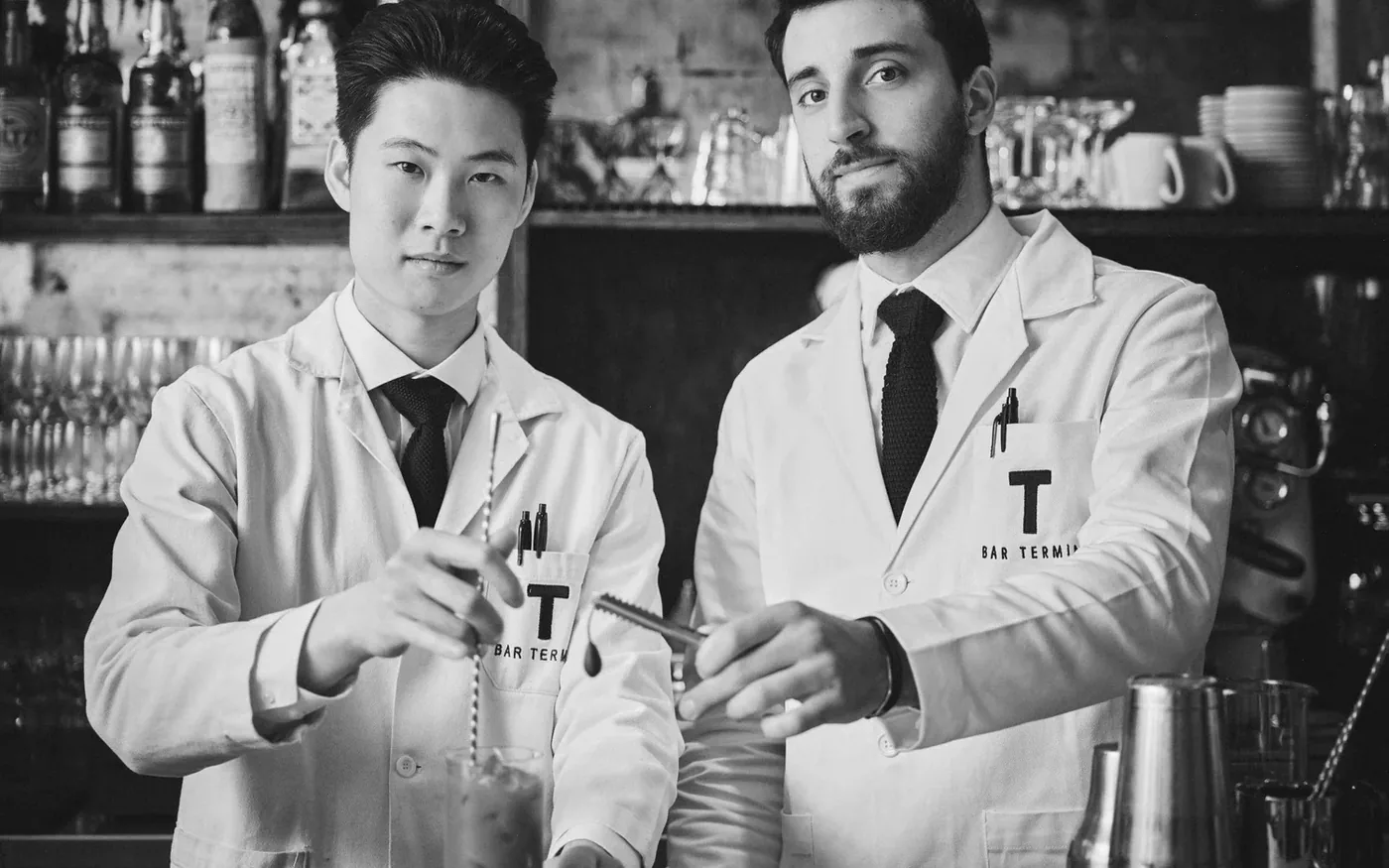 Two bartenders in Bar Termini coats making drinks at the bar in Soho, London