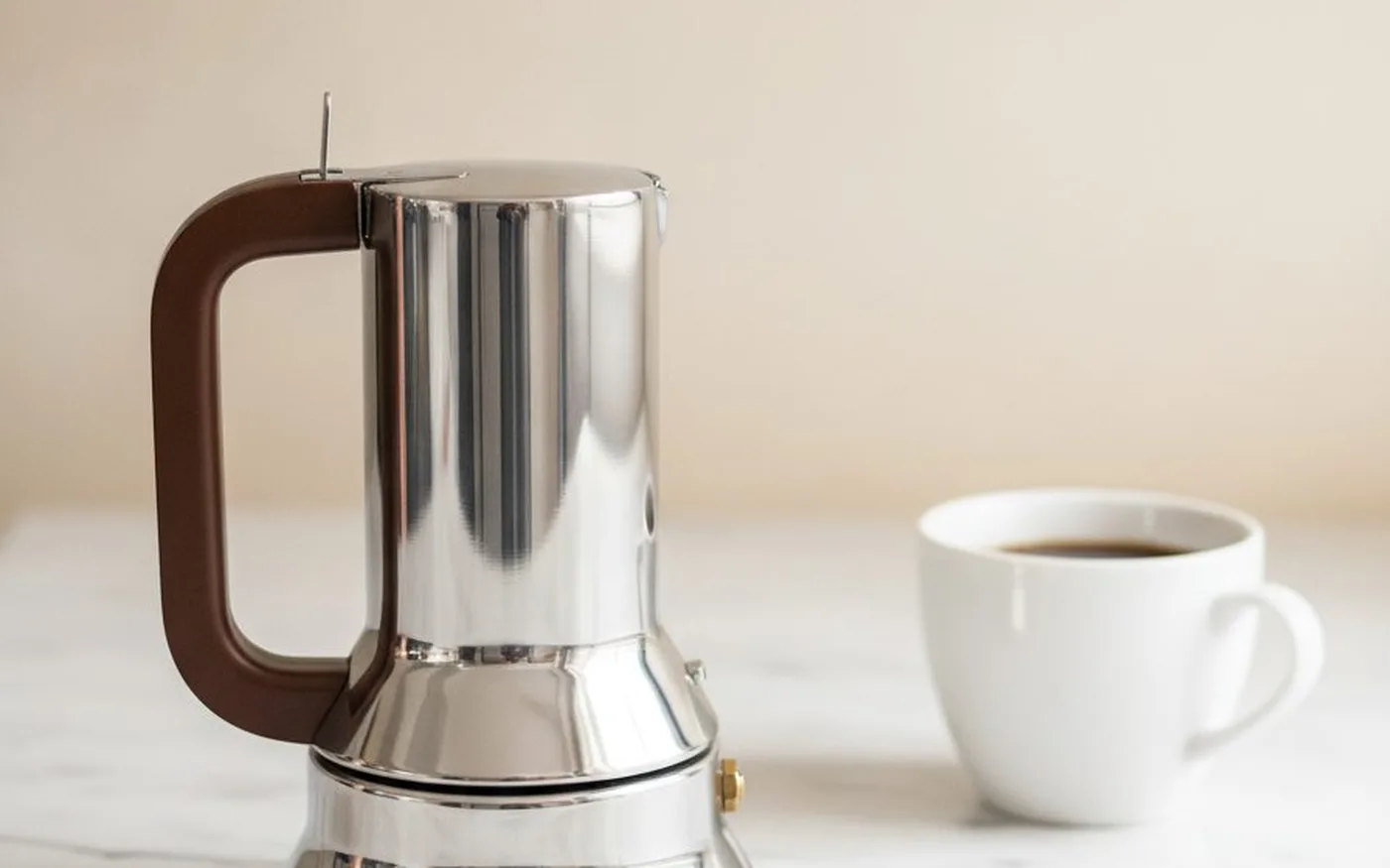 Alessi 9090 stainless steel 3-cup showing the award-winning form and flip lid on a kitchen countertop