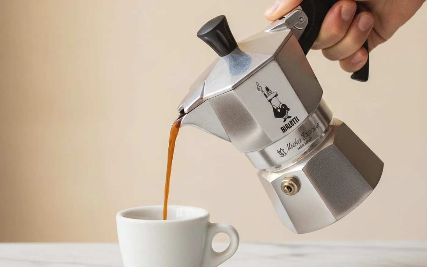 Pouring freshly brewed moka pot coffee into espresso cup