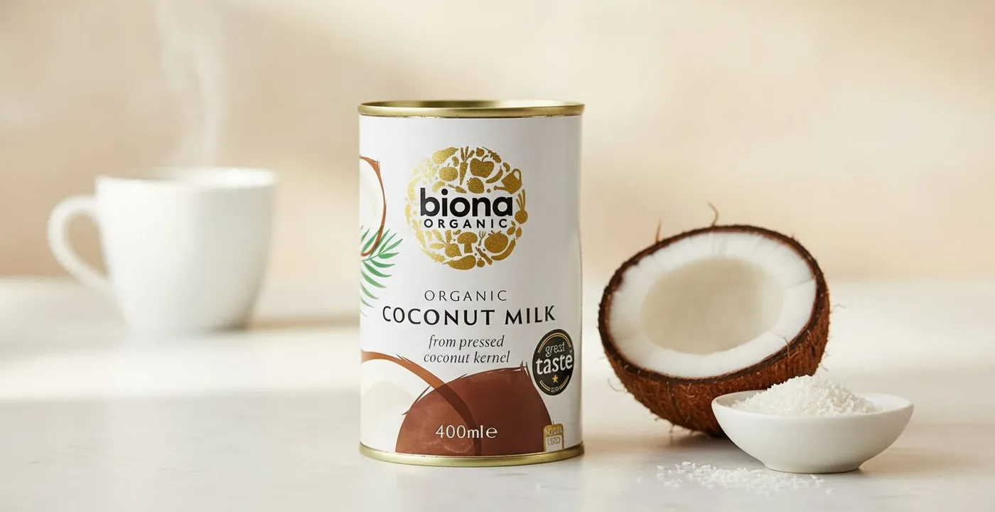 Biona organic coconut milk 400ml can on a kitchen counter with a cup of filter coffee