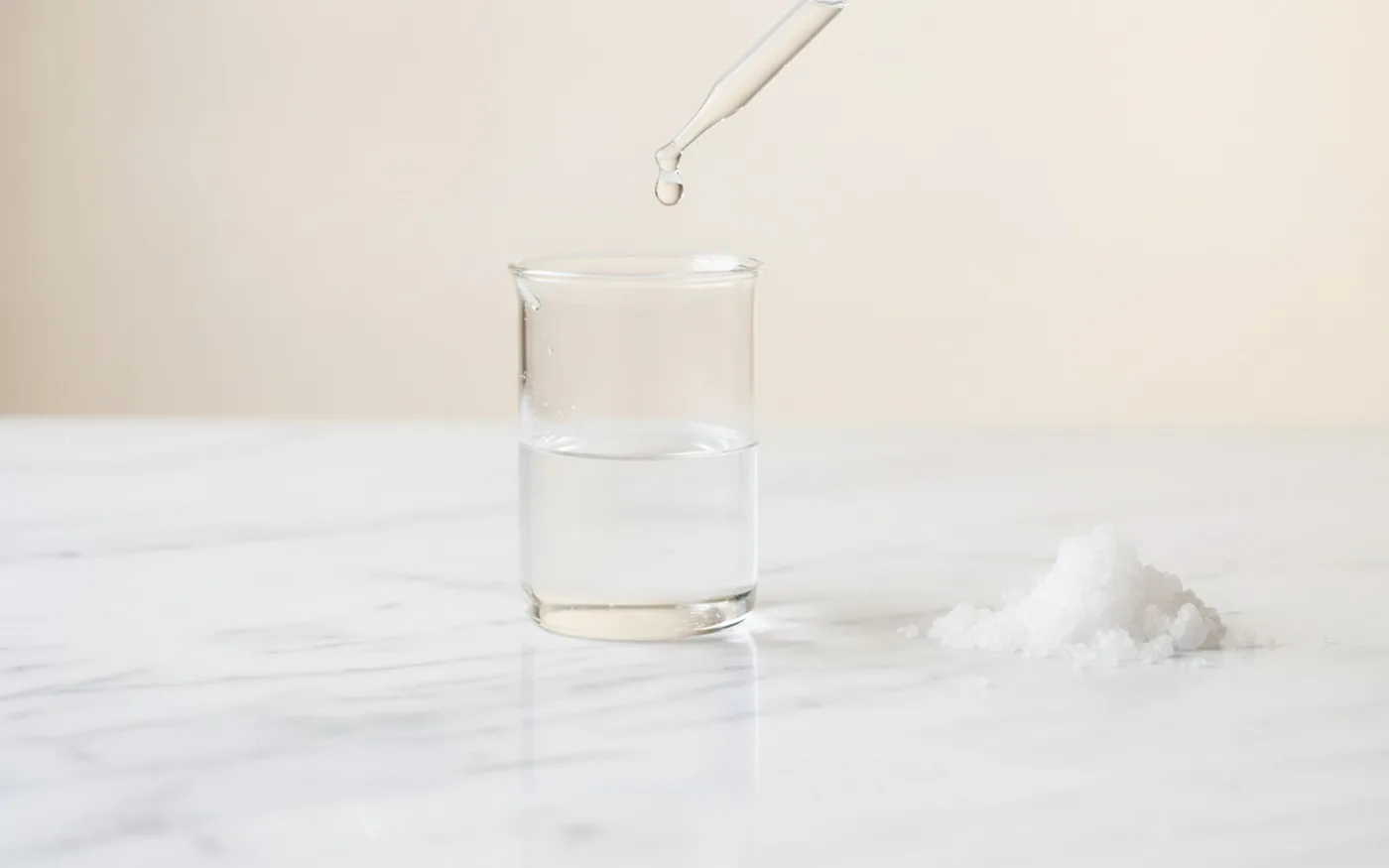Lab beaker and pipette beside salt crystals, evoking formulation testing