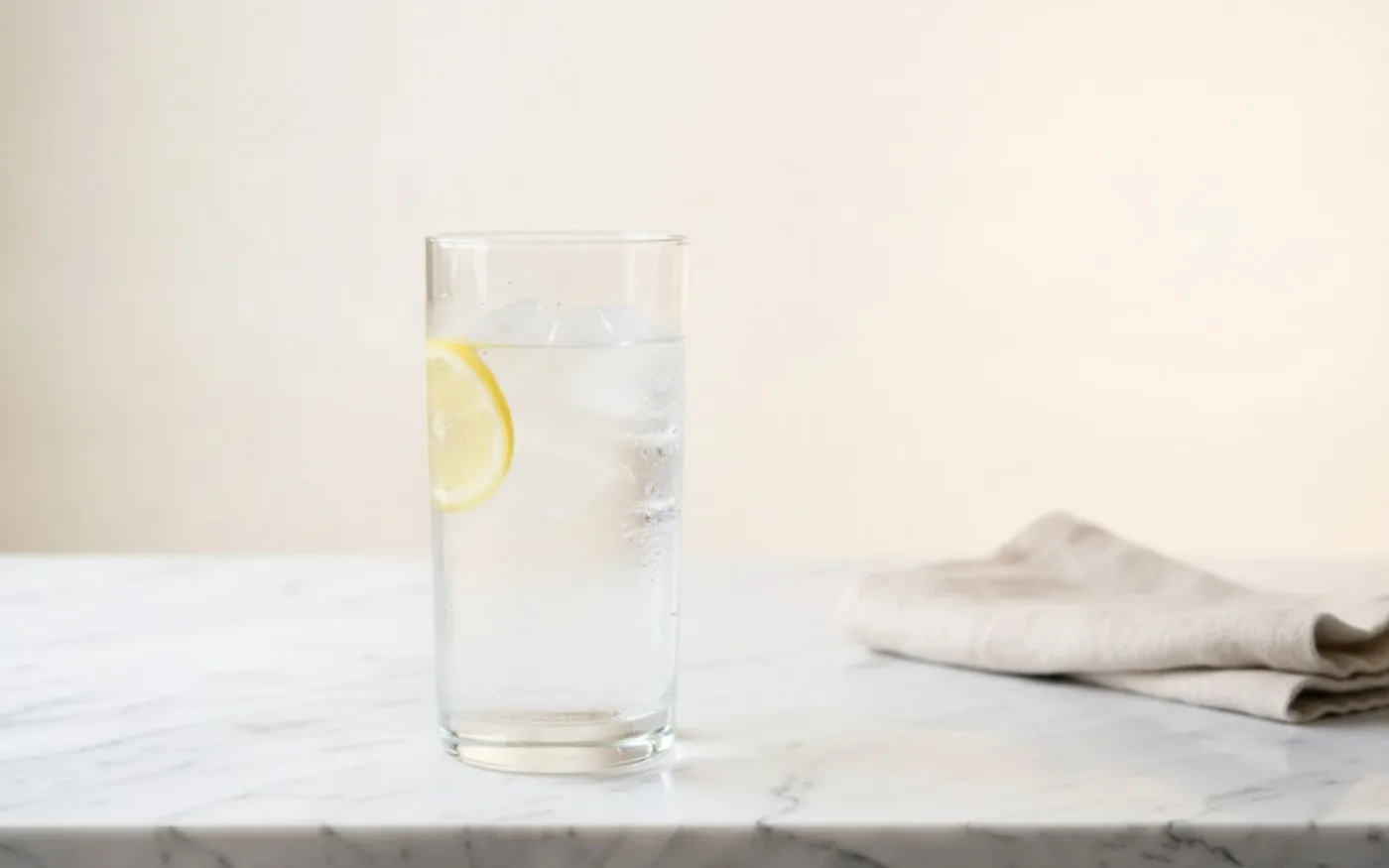 Glass of water with ice and lemon on marble