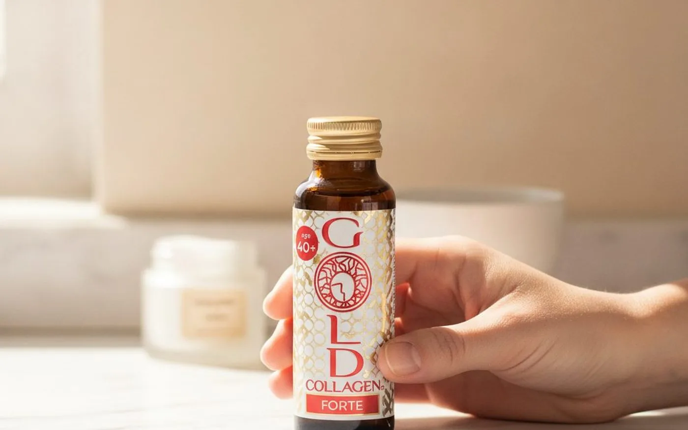Gold Collagen Forte liquid shot bottle held in hand, showing the amber glass bottle with gold cap and branded label