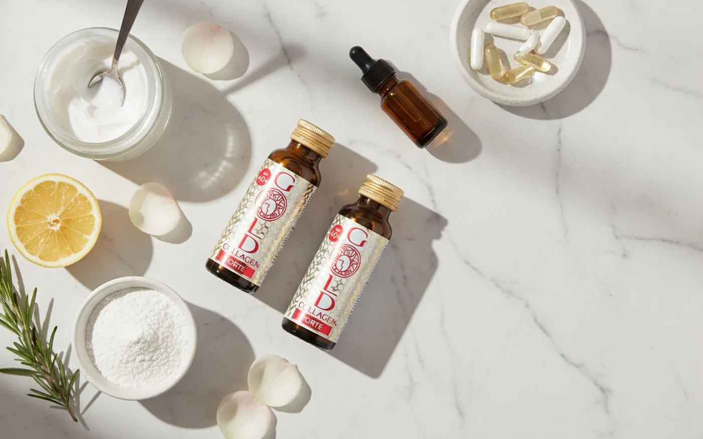 Gold Collagen bottles in a wellness flatlay with skin health ingredients including lemon and vitamin supplements