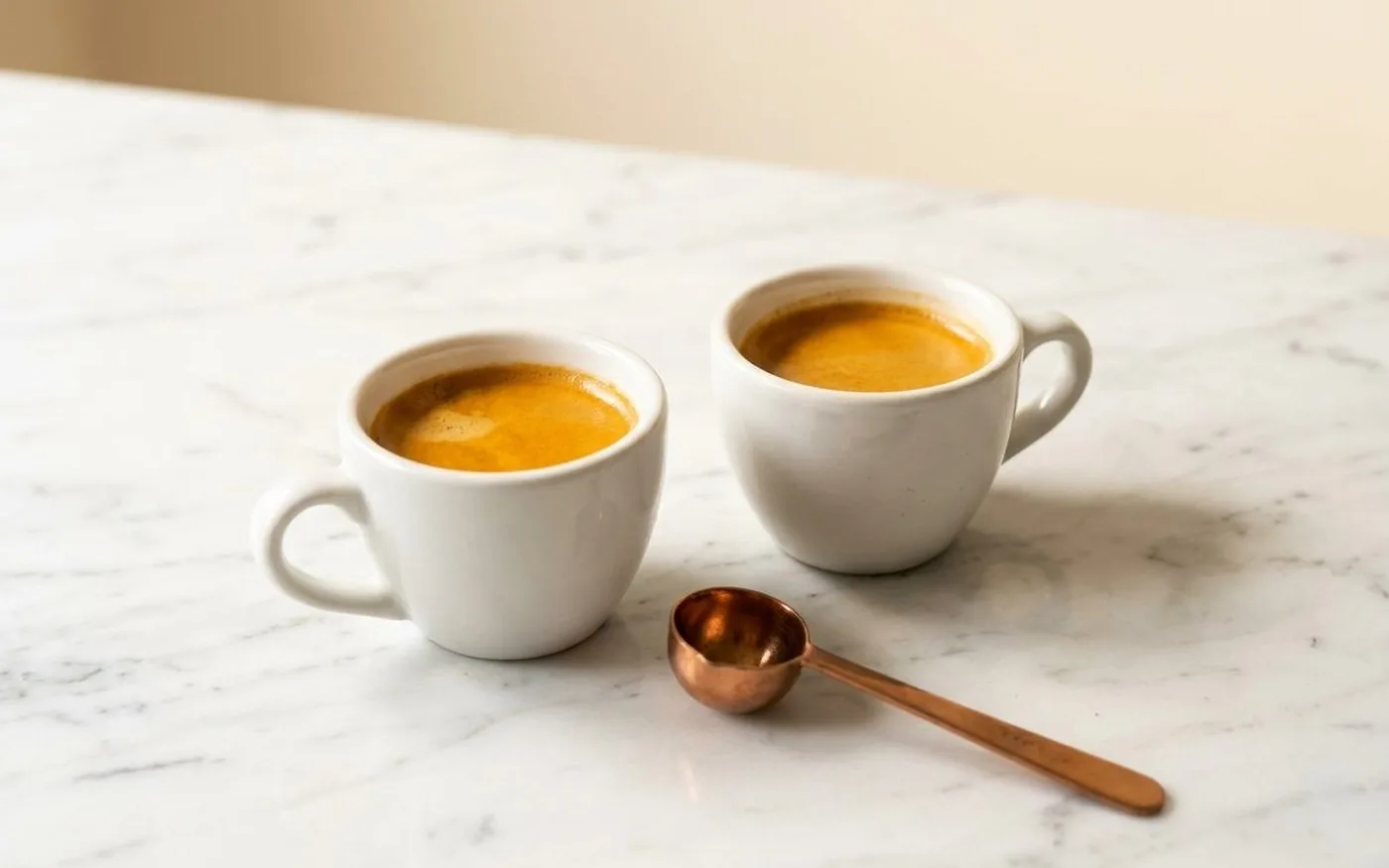 Two espresso cups side by side on white marble counter for taste comparison