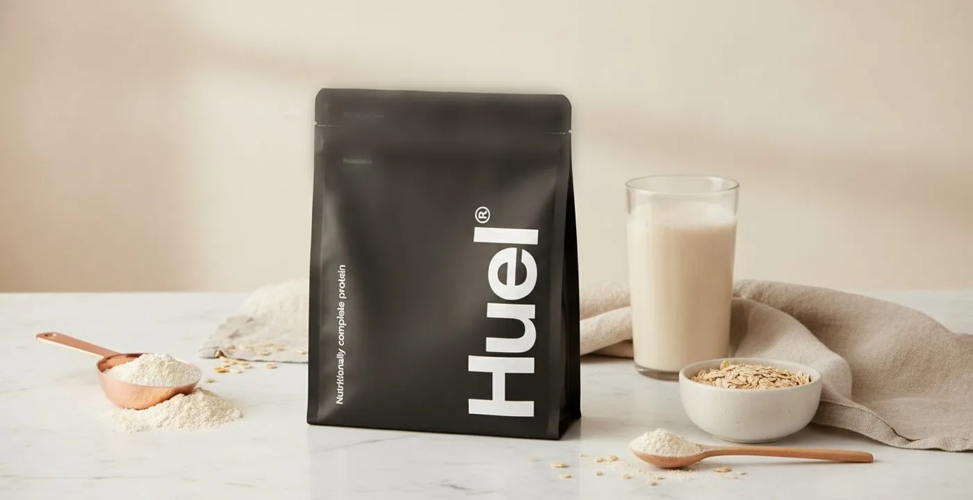 Huel Complete Protein powder bag and shake on white marble surface