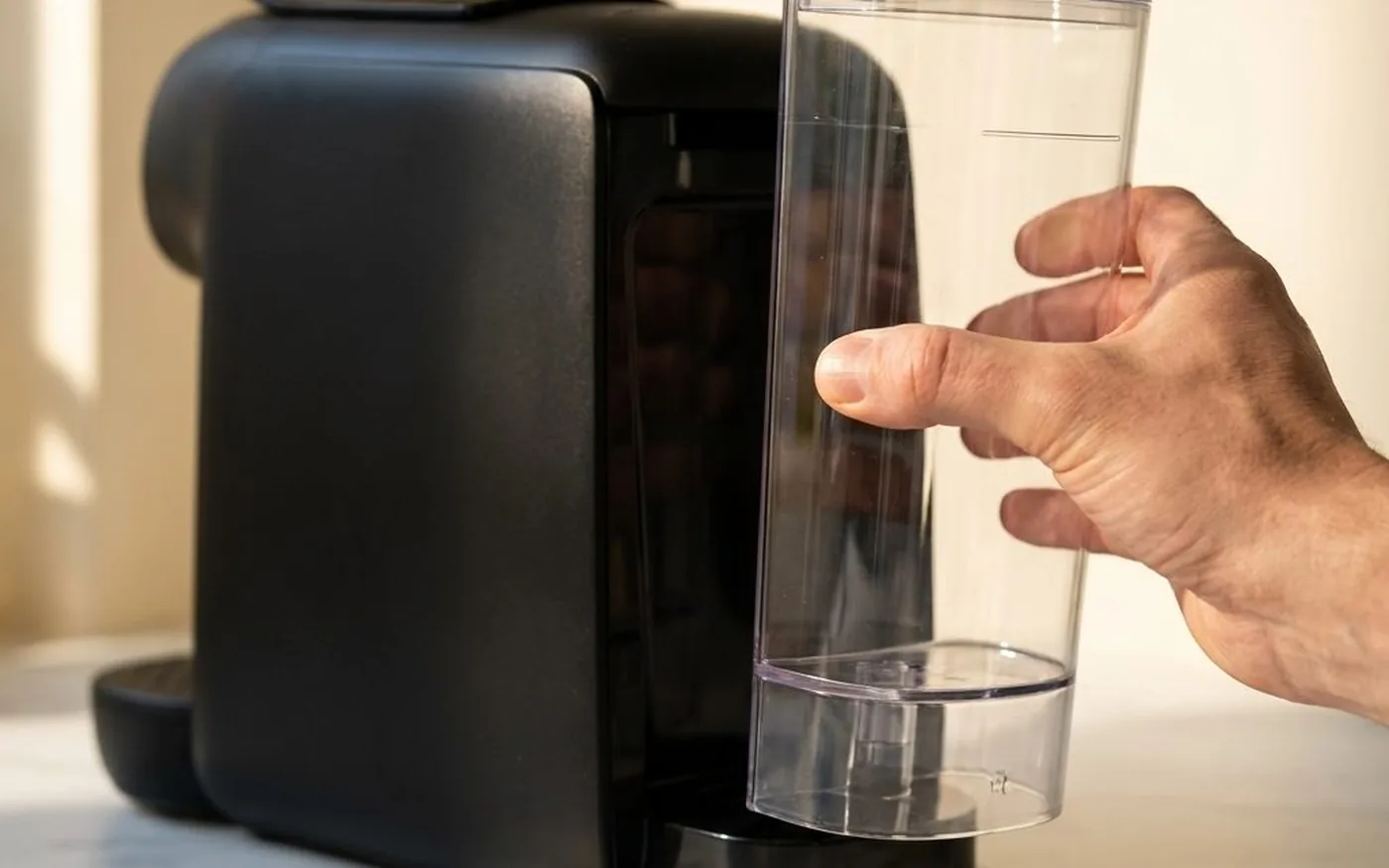 Oat milk being poured from a ceramic jug into an espresso cup on a white marble countertop