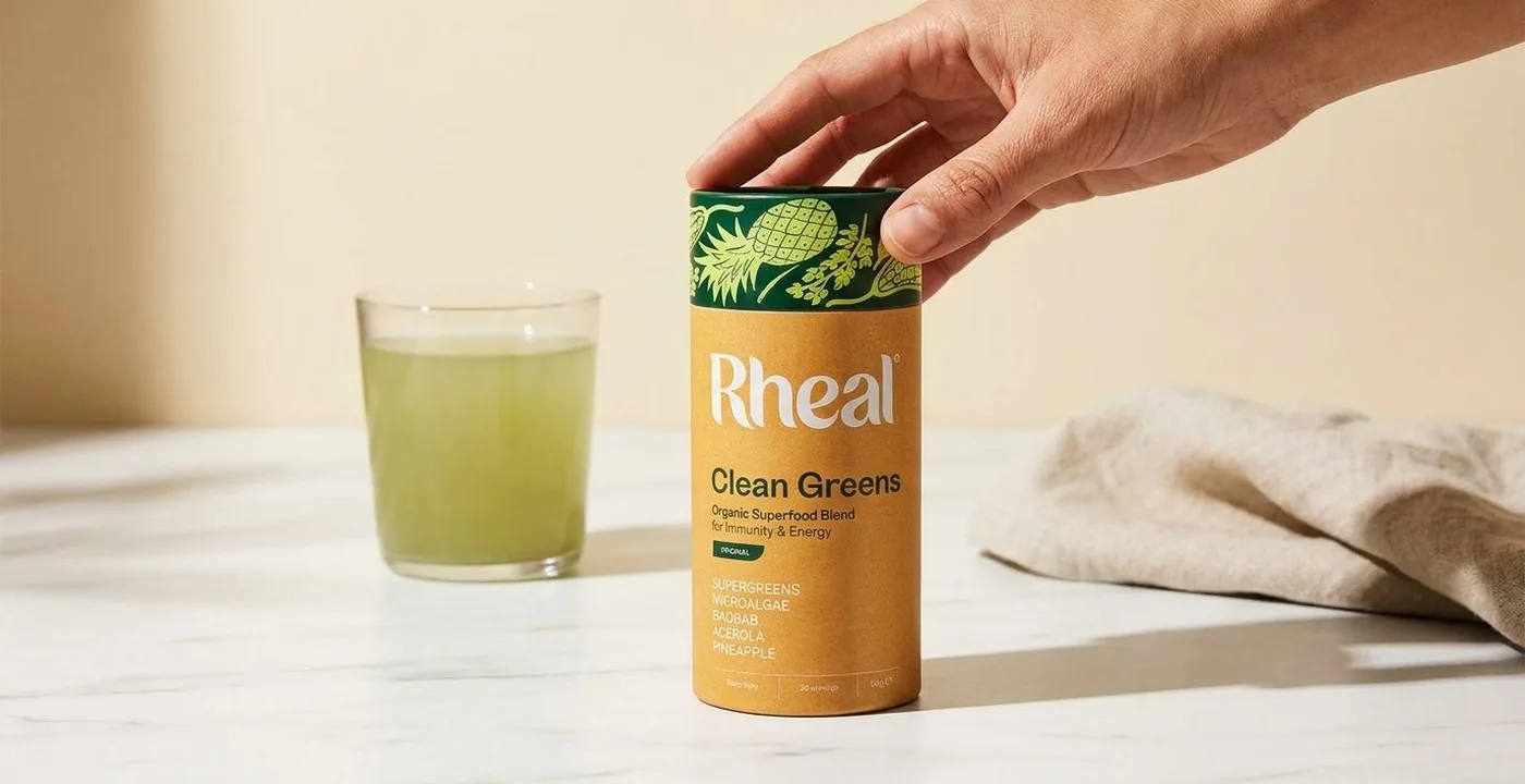 Rheal Clean Greens superfood blend pouch on a white marble surface