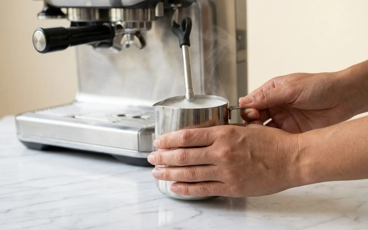 Hands steaming milk with espresso machine steam wand for flat white