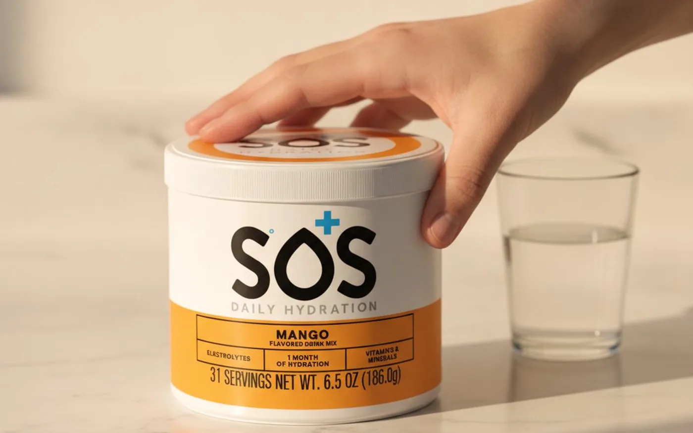 Electrolyte powder being poured into a glass of water on a white marble surface