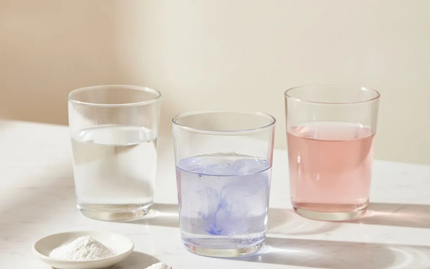 SOS Daily Hydration tub on white marble countertop with a glass of water