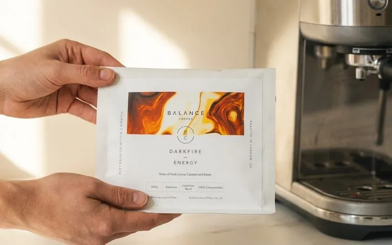 Balance Coffee Darkfire Energy coffee bag held by two hands on white marble with espresso machine in background